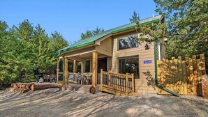 A lodge with a covered porch, a wooden deck, and a gravel driveway. - 2 Level Cabin w/Hot Tub & Fireplace. 1.5 Bathrooms, 2 Queen Beds (Ashland)