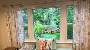 Ein Schlafzimmer mit einem Bett, Kissen, einem kleinen Tisch und einem Fenster mit Vorhängen.
