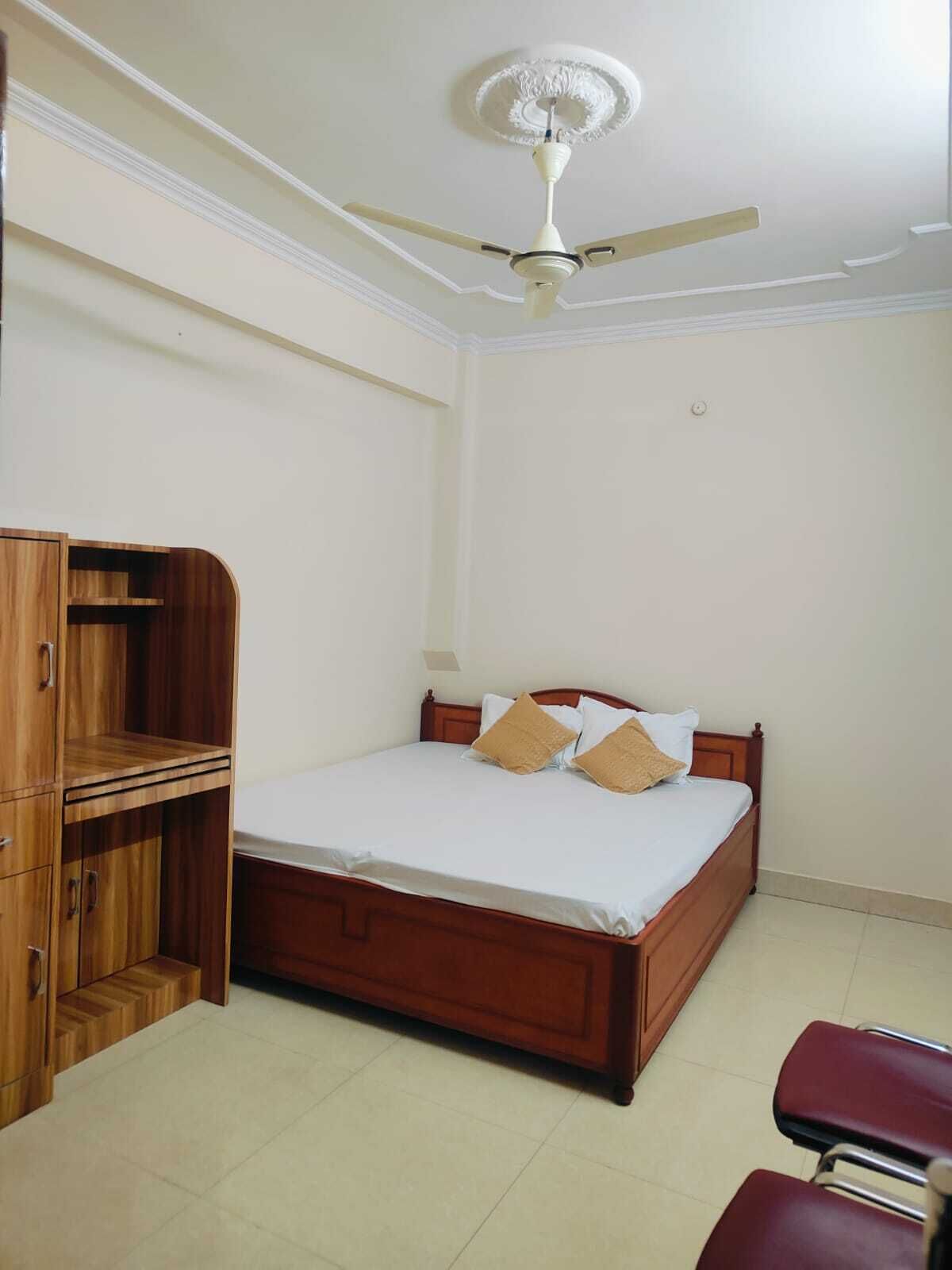 A bedroom with a wooden bed, a ceiling fan, and a wooden wardrobe.
