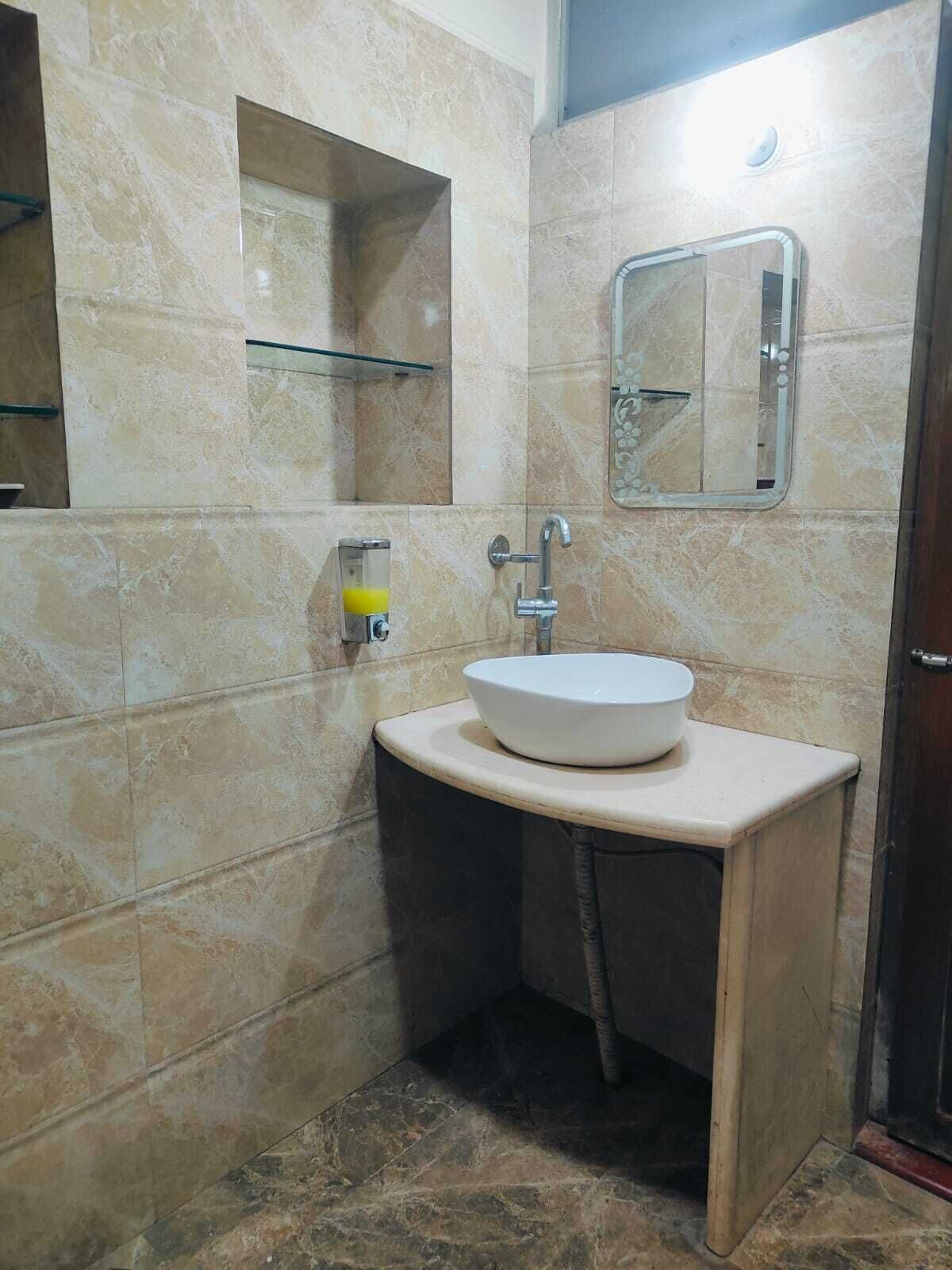 A bathroom with a white sink, a mirror, and a glass shelf.