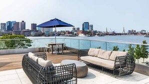 A rooftop terrace with outdoor furniture, a table, and an umbrella.