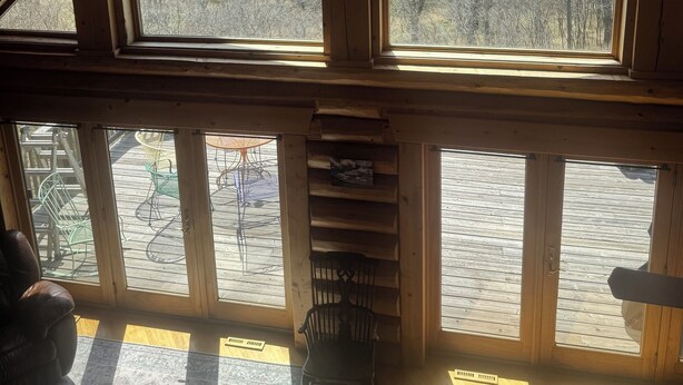 A cabin with a sloped roof, large windows, a wooden interior, and a view of a forested landscape. - Beautiful log cabin, only 1.7 miles from lake dock by Lewis & Clark, Yankton SD (Yankton)