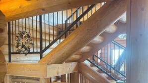 A wooden staircase with a metal railing, a wooden door with a doormat, and a pair of slippers on the floor. - Beautiful log cabin, only 1.7 miles from lake dock by Lewis & Clark, Yankton SD (Yankton)