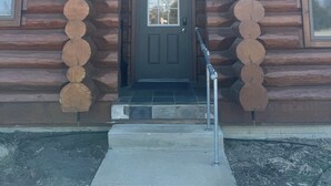A log cabin with a dark brown door, a small window above the door, and a set of stairs leading up to the entrance. - Beautiful log cabin, only 1.7 miles from lake dock by Lewis & Clark, Yankton SD (Yankton)