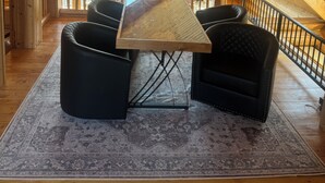 A cozy attic room with a wooden ceiling, a ceiling fan, a large window, a wooden table, and black leather chairs. - Beautiful log cabin, only 1.7 miles from lake dock by Lewis & Clark, Yankton SD (Yankton)