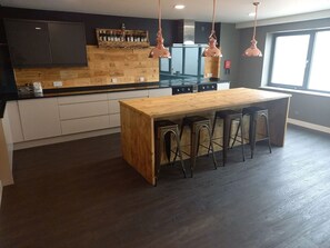 Une cuisine moderne avec un îlot central en bois, des tabourets de bar et des luminaires suspendus.