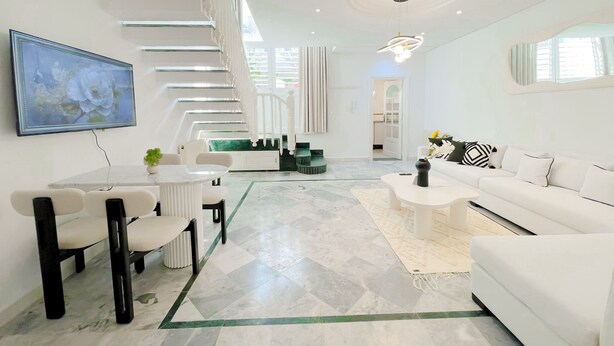 A modern living room with a staircase, a dining area, and a sofa. - La Petite Maison Charme en Bord de mer (Carthage)