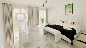A modern bedroom with a large bed, a bench, a round window, and a green wall. - La Petite Maison Charme en Bord de mer (Carthage)