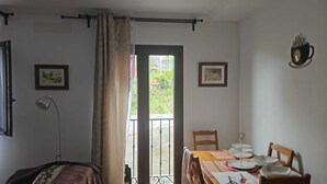 Une pièce comprenant un lit, un bureau, une chaise, une table dressée pour le repas, une fenêtre avec des rideaux et deux tableaux encadrés accrochés au mur.