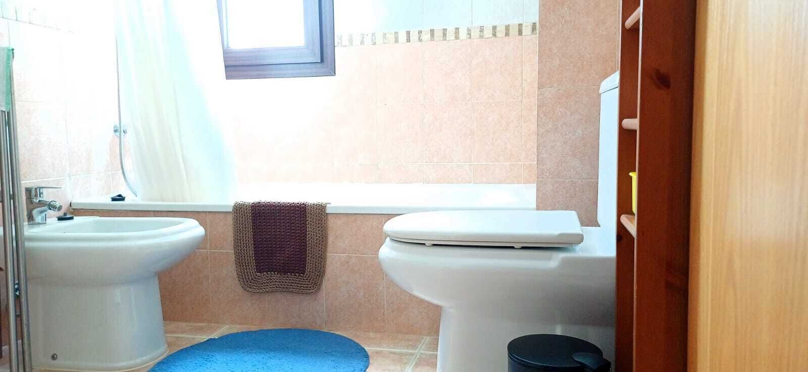 Un baño con dos inodoros, un bidé y una ventana.
