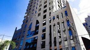 A tall, modern building with a prominent central entrance and multiple floors. - Nobile Grand Itapema (Itapema)