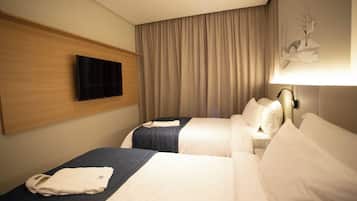 A hotel room with two beds, a flat-screen TV mounted on the wall, a lamp, and a painting on the wall.