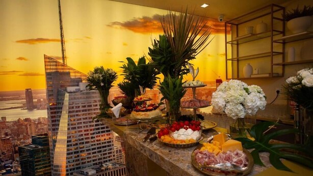 A buffet table with various food items and a cityscape view in the background. - Nobile Grand Itapema (Itapema)