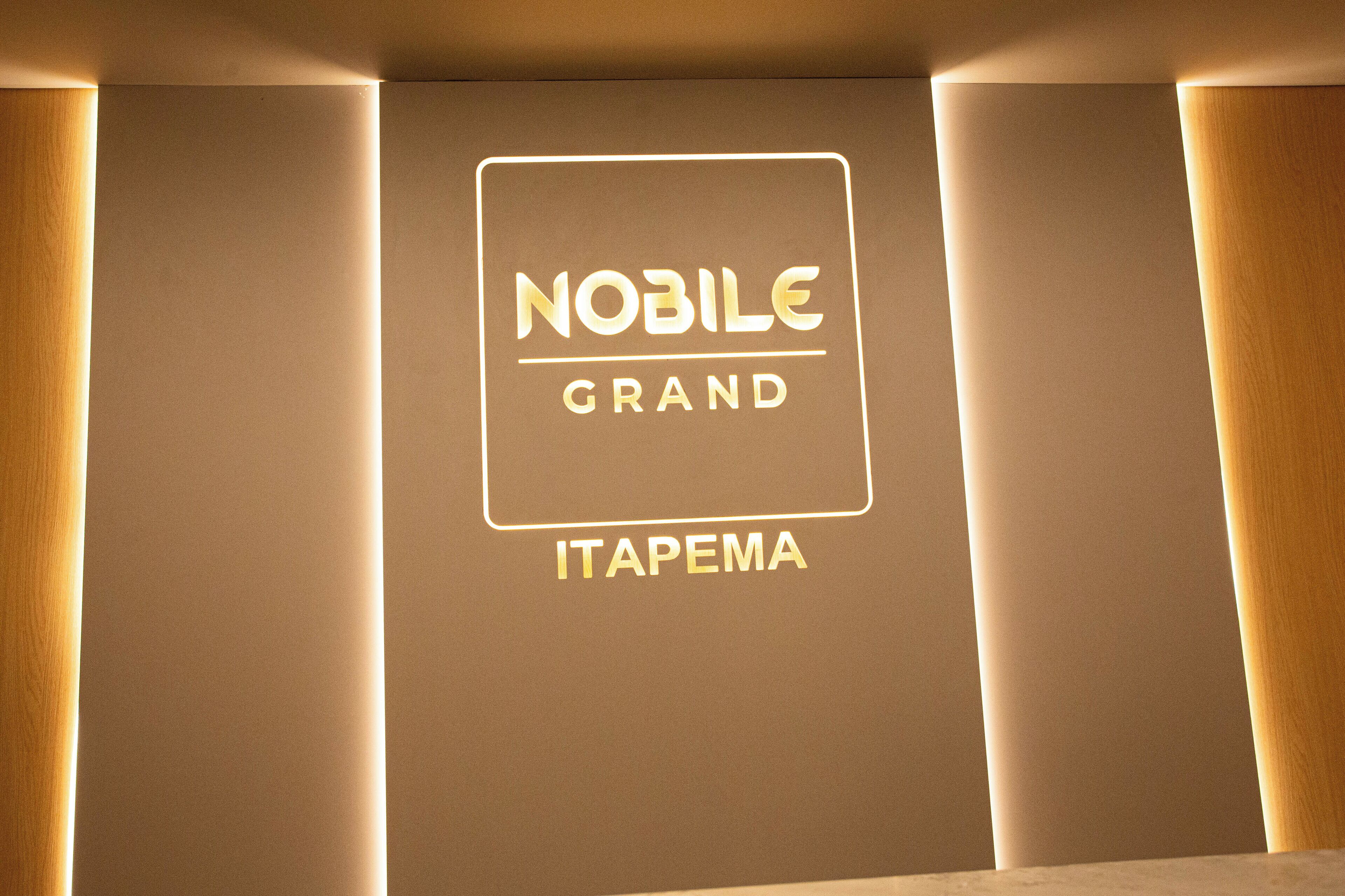 Uma parede com letreiros de neon que exibem os dizeres 'NOBILE GRAND' e 'ITAPEMA'.
