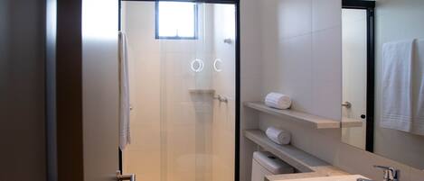 A modern bathroom with a glass shower door, a toilet, a sink, and a mirror.