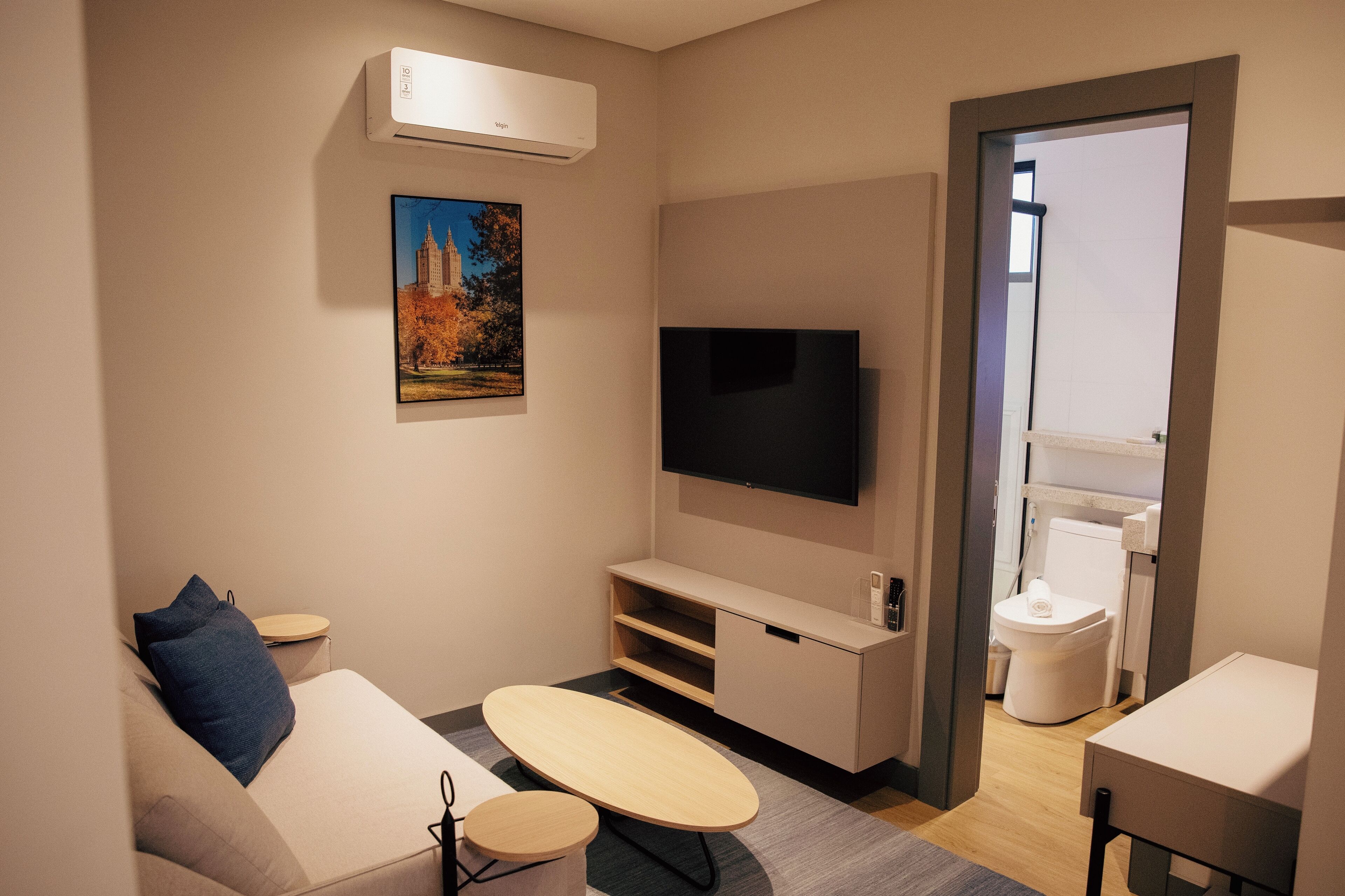 A modern living room with a flat-screen TV, a sofa, a coffee table, and a small side table.