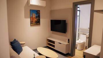 A modern living room with a flat-screen TV, a sofa, a coffee table, and a small side table.