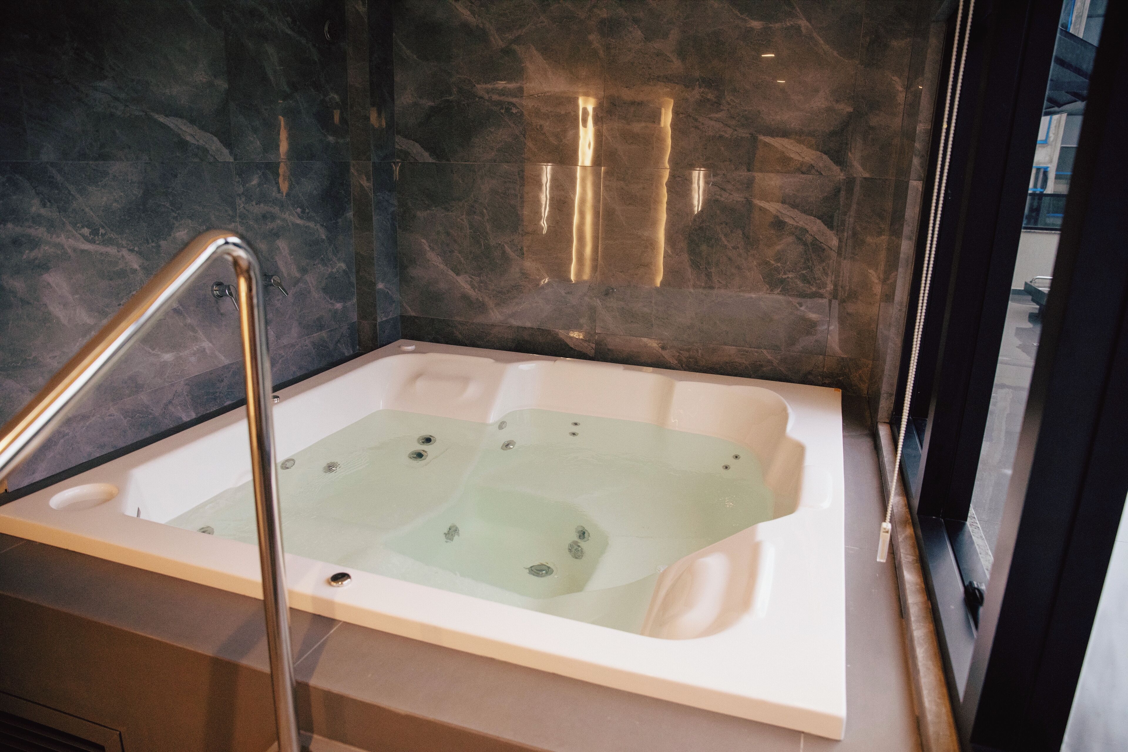 A modern bathroom with a freestanding bathtub, marble walls, and a glass shower enclosure.