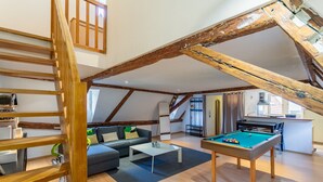 A loft-style living room with exposed wooden beams, a pool table, a sofa, and a staircase. - Le Cocon Alsacien - Appt authentique coeur strasbourg (Strasbourg)