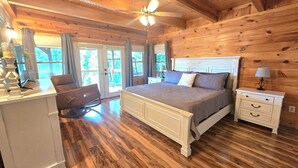 A wooden cabin bedroom with a bed, nightstands, and a desk.
