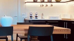 A modern kitchen with a wooden dining table, black chairs, and a chandelier. - Residence19 ilborgo (Asolo)