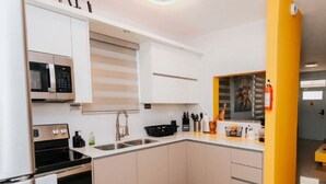 Una cocina moderna con armarios blancos, una estufa negra, un microondas y un fregadero.