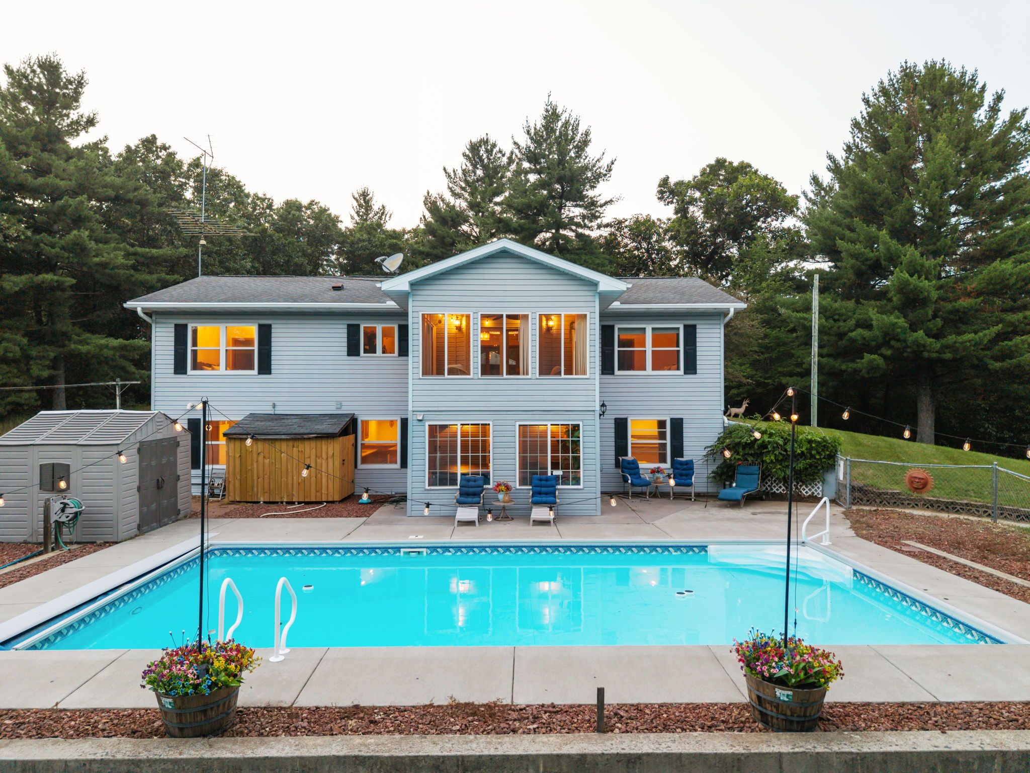 Ein zweistöckiges Haus mit Pool, Sitzgelegenheiten im Freien und einem umzäunten Garten.