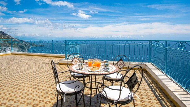 Ein Essbereich mit Tisch für vier Personen, Stühlen und Blick aufs Meer.