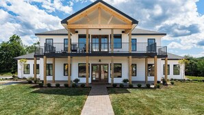 A two-story house with a covered front porch, large windows, and a balcony.