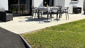 A patio with a table and chairs, a small window, and a sliding glass door.