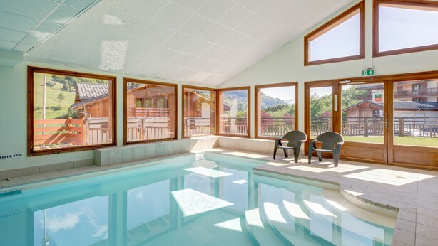 Ein Schwimmbad mit freiem Blick auf eine gebirgige Landschaft durch große Fenster.