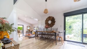 A spacious living area with a dining table, chairs, and a large window offering a view of greenery.