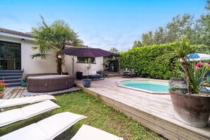 Relax on the deck with lounge chairs and a shaded seating area, surrounded by lush greenery and a small pool.