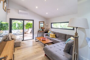 Relax in this stylish living room with a sofa, coffee table, side table, and floor lamp, plus access to an outdoor patio.
