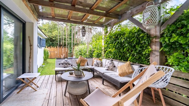 A wooden deck with a sofa, chairs, and a small table.