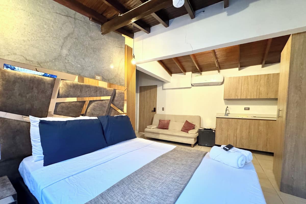 Une chambre comprenant un lit, un canapé, une petite table et un coin cuisine.