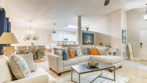 A modern living room with a sofa, coffee table, and a dining area with chairs and a table.