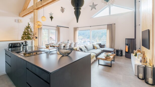 A modern kitchen with a central island, a cozy seating area with a sofa and coffee table, and a fireplace. - L’Alma - Magnifique maison avec jacuzzi (Gérardmer)