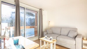 A room with a sofa, a table with a bottle, glasses, and a cup.