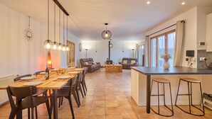 A spacious living area with a dining table, sofas, and a kitchen island.
