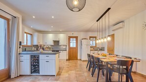 A spacious kitchen with white cabinets, a central island, and a dining area with a table and chairs.