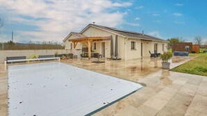 A house with a covered patio, a swimming pool, and a garden.