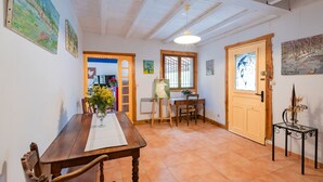 A dining area with a wooden table and chairs, a vase of flowers, and a painting on the wall. - Le Coteau Ensoleillé - Climatisée avec piscine (Carcassonne)