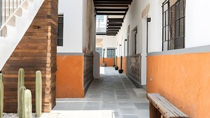 A corridor with a wooden staircase on the left, a bench on the right, and a row of windows along the walls. - Casona 212 | Stylish Loft w/ High-Speed WiFi (Puebla)