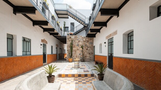 A courtyard with a checkered floor, potted plants, and a staircase leading to an upper level. - Casona 212 | Stylish Loft w/ High-Speed WiFi (Puebla)