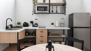 A modern kitchen with a microwave, coffee maker, and refrigerator. There is a sink with a faucet, a countertop with various appliances, and a dining area with chairs and a table. - Casona 212 | Stylish Loft w/ High-Speed WiFi (Puebla)