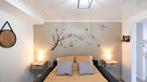 A bedroom with a bed, two bedside tables, and a wall mural.