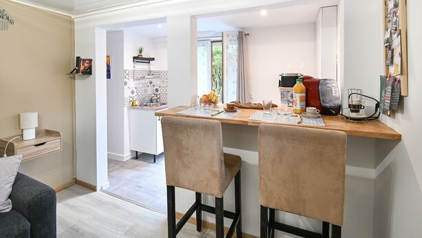 A modern kitchen with a wooden countertop, two bar stools, and a coffee machine.