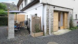A small house with a stone facade, a wooden door, and a small garden area with a table and chairs.