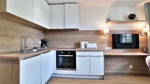 A modern kitchen with white cabinets, a built-in oven, and a coffee maker. - Paulette 14 - A Sables d'Or les pins, proche plage (Fréhel)